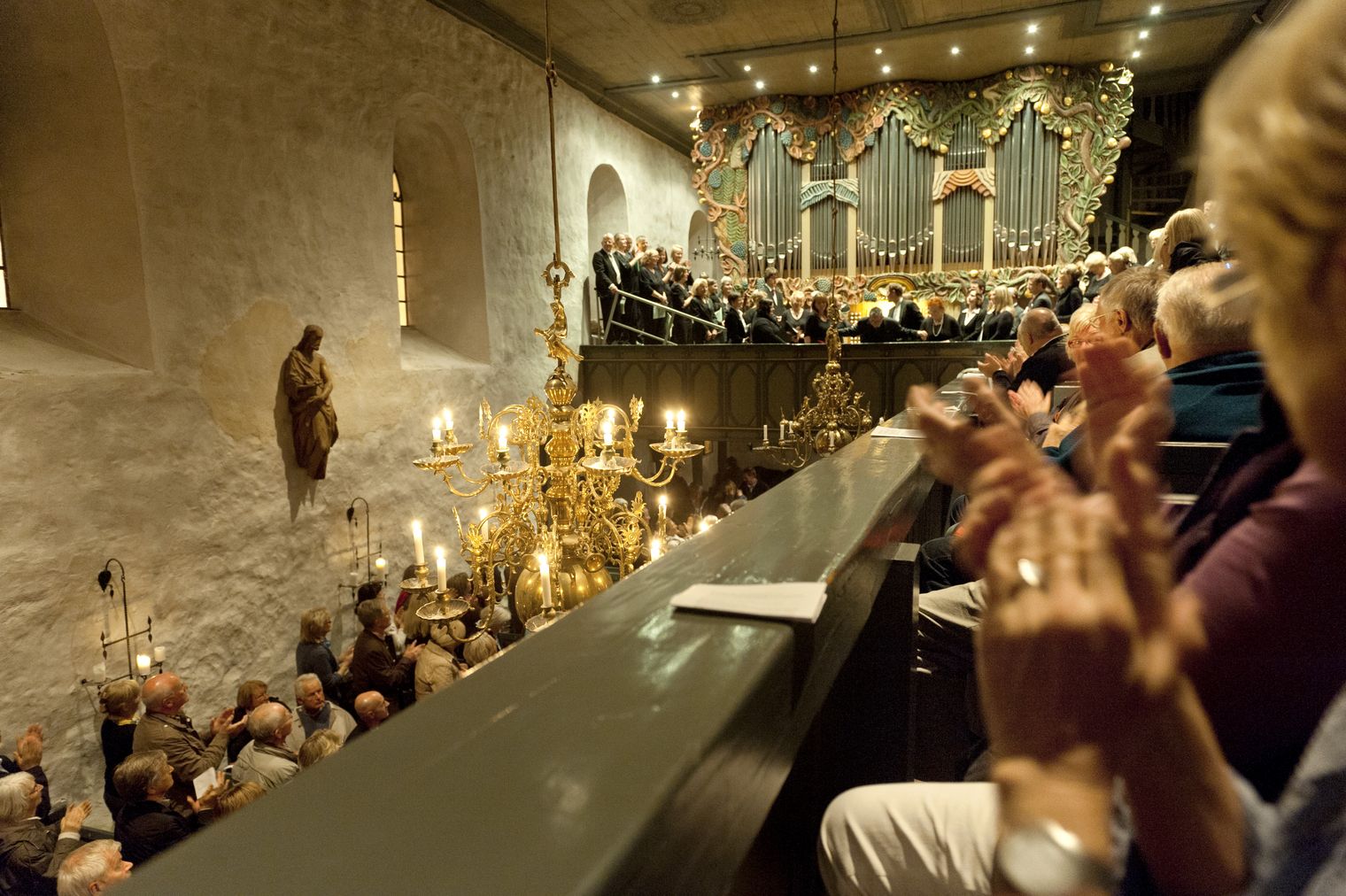 Kirchenkonzert mit Orgel, Chor und Publikum, das begeistert applaudiert.