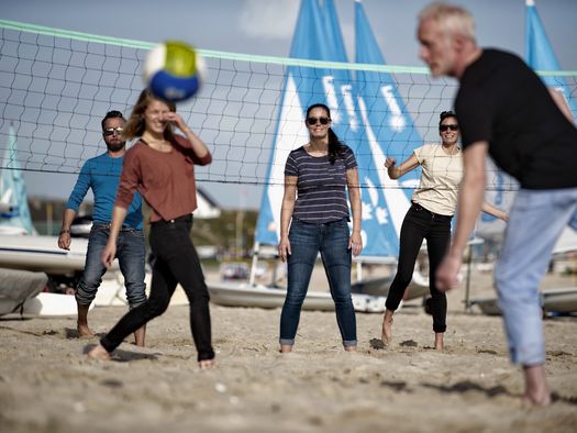 Am Strand in Hörnum spielen zwei Teams zusammen Volleyball.