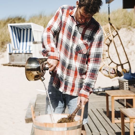 Ein Mann macht einen Aufguss vor der Strandsauna List.