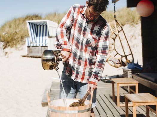 Ein Mann macht einen Aufguss vor der Strandsauna List.