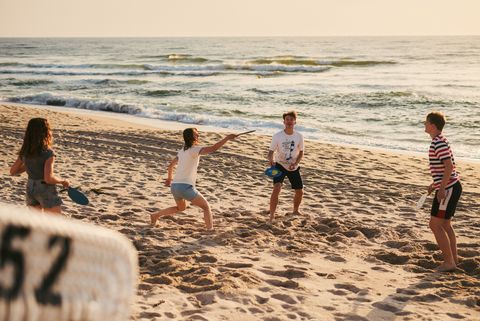 Vier Personen spielen Strandtennis im Abendlicht vor der Nordsee.