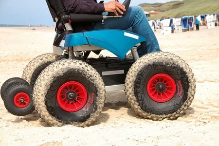 Ein CadWeazle-Geländefahrzeug mit großen, grobstolligen Reifen für die Fahrt am Strand. Der Fahrer ist teilweise sichtbar und steuert das Fahrzeug über den Sand.