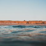 Blick vom Wasser auf das Rote Kliff mit Strandkörben.