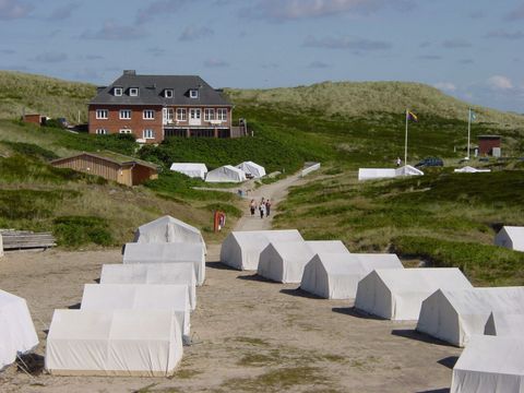 Ein Zeltplatz in Hörnum auf Sylt, der Jugendzeltplatz Möskendeel, eingerahmt von Dünen und dem Meer im Hintergrund.