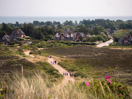 Sandiger Pfad zur Uwe-Düne mit Reetdachhäusern und grüner Umgebung auf Sylt.