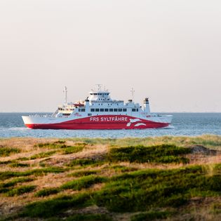 Die FRS Syltfähre Rømø Express gleitet sanft über das Wasser, während die Sonne das Wattenmeer in ein warmes Licht taucht. 