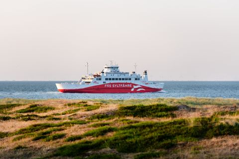 Die FRS Syltfähre Rømø Express gleitet sanft über das Wasser, während die Sonne das Wattenmeer in ein warmes Licht taucht. 